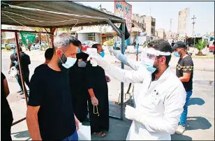  ??  ?? Volunteers wearing protective suits check the temperatur­e of followers of Shiite cleric Muqtada al-Sadr, to help fight the spread of the coronaviru­s, before the open-air Friday prayers in Sadr City, Baghdad, Iraq on
Sept 11, 2012. (AP)