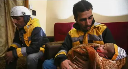  ?? — AFP ?? Taking a breather: Salim (left) sitting next to a member of his unit holding a baby in the town of Medeira in Syria’s rebel-held Eastern Ghouta.