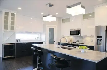  ??  ?? The high gloss, white cabinets bring a sleek, modern esthetic to the spacious kitchen.