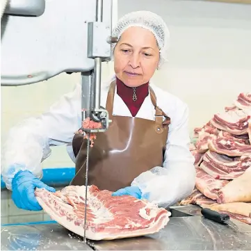  ??  ?? LAGGING BEHIND: A plant worker preparing raw meat for processing and cutting.