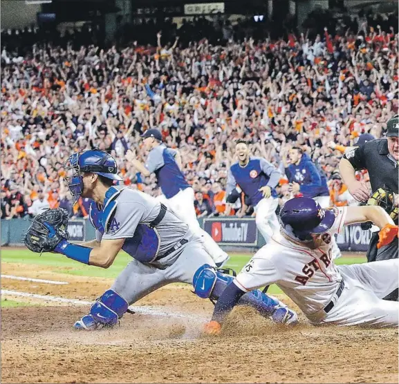  ??  ?? PINCH-RUNNER DEREK FISHER slides home with the winning run in the bottom of the 10th inning in Game 5 of the 2017 World Series as Austin Barnes waits for the throw and the crowd erupts. Alex Bregman delivered the winning hit with two outs against Kenley Jansen after Jansen hit Brian McCann and walked George Springer.