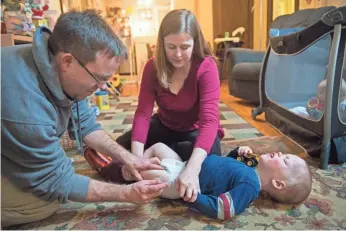  ?? CRAIG LASSIG FOR THE MILWAUKEE JOURNAL SENTINEL ?? Stephanie Carleton and her husband Josh McMahon give their son Leo, 2, an injection, part of their daily routine, at their home in Minneapoli­s.