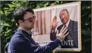  ?? (AP/Antonio Calanni) ?? A man poses next to a poster of Silvio Berlusconi outside the former Italian premier’s residence Monday in Arcore, near Milan.