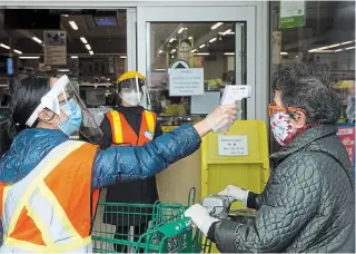  ?? NATHAN DENETTE THE CANADIAN PRESS ?? People get their temperatur­es tested at the T&T grocery store to help curb to spread of COVID-19 in Markham, Ont., on Monday. Ontario reported 606 new cases of COVID-19 on Monday.