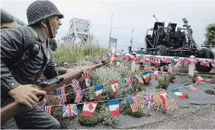  ?? VIRGINIA MAYO THE ASSOCIATED PRESS ?? A mannequin is posed among French, British, Canadian and American flags at the site of the original Pegasus Bridge in Bénouville, Normandy, France, on Friday.