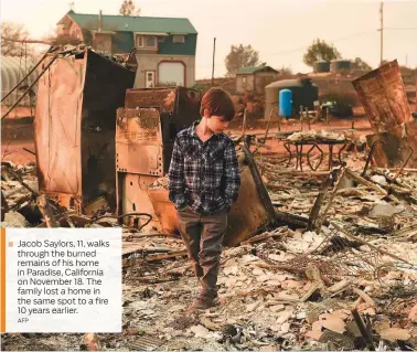  ?? AFP ?? Jacob Saylors, 11, walks through the burned remains of his home in Paradise, California on November 18. The family lost a home in the same spot to a fire 10 years earlier.