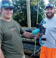  ??  ?? ■ Logan Lemley, left, and Jonathan Lenard display the bow used for fishing in a bow-and-arrow fishing tournament. A good bow with arrows costs in the neighborho­od of $400, Lemley said.