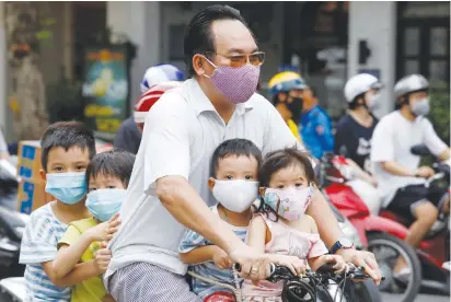  ?? (Kham/Reuters) ?? A MAN and his children ride a bicycle in Hanoi, Vietnam, yesterday.