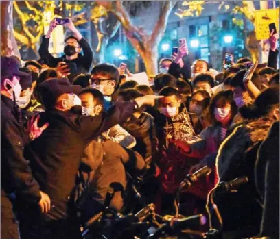  ?? ?? Police and people are seen during some clashes in Shanghai on Sunday, where protests against China’s zero-COVID policy took place the night before following a deadly fire in Urumqi, the capital of the Xinjiang region.