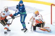  ?? CP PHOTO ?? Calgary Flames goalie David Rittich makes a save as Calgary’s Philip Samuelsson checks Jonah Gadjovich of the Vancouver Canucks on Wednesday night in Vancouver.