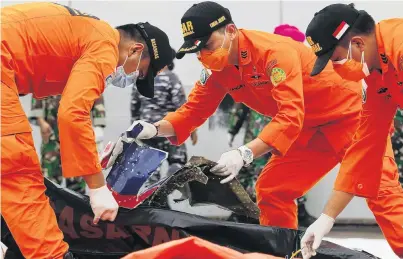  ?? PHOTO: REUTERS ?? Grim task . . . Indonesian rescue members inspect what is believed to be the remains of the plane from Sriwijaya Air flight SJ182, which crashed into the sea, at Jakarta Internatio­nal Container Terminal port in Jakarta, Indonesia, yesterday.