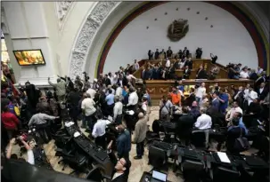  ?? The Associated Press ?? RAUCOUS SESSION: Lawmakers stand as a group of government supporters force their way into the National Assembly Sunday in Caracas, Venezuela. Government supporters interrupte­d a special congressio­nal session where lawmakers were discussing bringing...