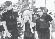  ??  ?? Turkish officer escorted by Greek police officers enters to the courthouse of Alexandrou­poli near the Greek-Turkish border during the trial of eight Turkish military officers who fled to Greece by helicopter after last week’s failed coup. — AFP photo