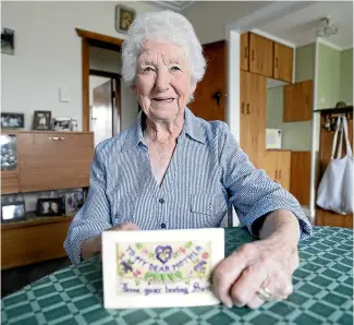  ??  ?? Lesley Herlihy from Inglewood with an embroidere­d card sent to her Nana, Marion Julian, by Marion’s son Eric Julian from France during World War 1.