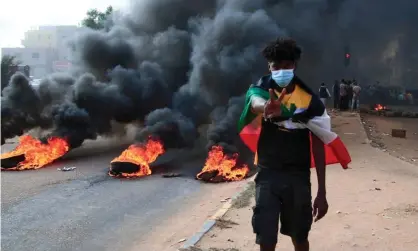  ?? ?? A protester draped in Sudan’s flag flashes the victory sign next to burning tyres during a demonstrat­ion in Khartoum. Photograph: AFP/ Getty Images