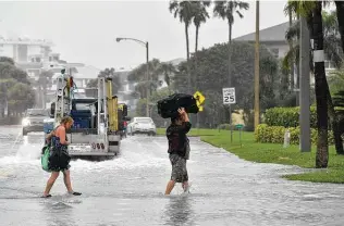  ?? Mike Lang / Associated Press ?? Hotel guests carry luggage to their car on Lido Key in Sarasota, Fla., on Wednesday morning as Hurricane Eta passed in the Gulf. Eta was downgraded to a tropical storm as it neared Tampa.