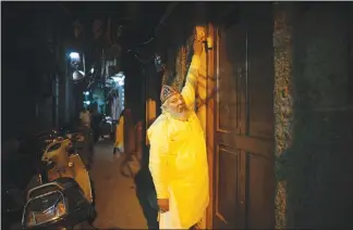  ??  ?? Shafiq knocks on a door to wake neighbors for a pre-dawn meal during Ramadan. “It’s lonely work and when I go, the tradition will die, too,” he said.