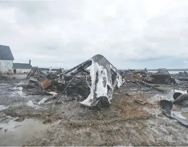  ?? ANDREW VAUGHAN / THE CANADIAN PRESS ?? Debris from a burned-out fish plant is scattered along the shore in Middle West Pubnico, N.S., on Saturday. The building was the scene of a confrontat­ion last week between Indigenous and non-Indigenous fishermen.