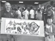  ?? YU FANGPING / FOR CHINA DAILY ?? Klaus Schlappner, the first foreign coach to manage the Chinese national soccer team, receives a gift from a child at a kindergart­en in Qingdao on Wednesday in an event to promote youth soccer exchanges between China and Germany. Schlappner, who is German, managed the Chinese team from 1992 to 1993 and led the team to the semifinals of the 1992 AFC Asian Cup.