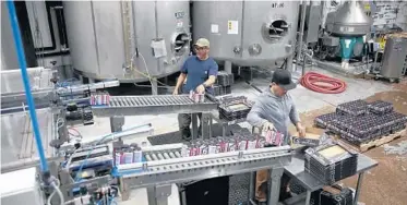  ?? ?? Armando Renovapo, rear, and Juan Renovapo package freshly canned beer at Two Brothers Brewing.