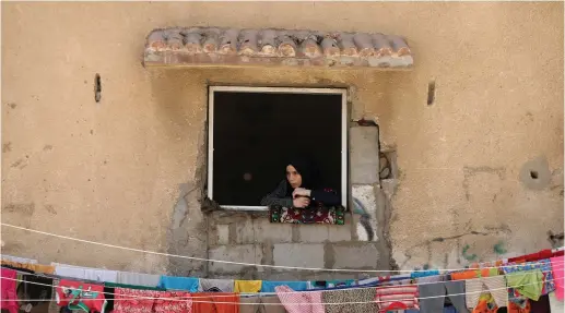  ?? (Reuters) ?? A WOMAN looks out a window in the Gaza Strip.