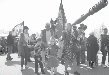  ?? ALEXEI ALEXANDROV/AP ?? Ukraine remembers: A girl wearing Soviet-era military uniform and her relatives walk during Victory Day celebratio­ns Saturday at a World War II memorial in Saur-Mogila, Ukraine, near the Russian border. Efforts have stalled to end the conflict between Russia-backed rebels and Ukrainian forces that’s killed more than 14,000 people since 2014.