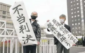  ?? KYODO NEWS VIA AP ?? Plaintiff Katsuhiro Hirano (right) and an unidentifi­ed lawyer for plaintiffs hold signs after losing a judgment in Hiroshima court that sought health benefits for the children of survivors of the U.S. atomic bomb attack.