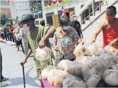  ?? WICHAN CHAROENKIA­TPAKUL ?? A monk hands out food in Klong Toey. The temple cooks large amounts of food daily to be given free to those affected by the coronaviru­s.