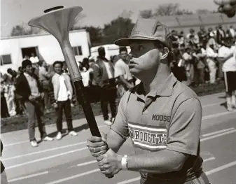  ?? Charles Cherney / Associated Press file ?? Michael Cusack carries the torch around the track at the University of Chicago’s Stagg Field during the Special Olympics opening ceremony in May 1988. He has died at age 64.