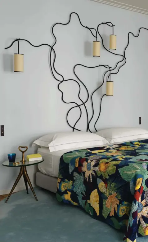  ??  ?? En el dormitorio principal, la cama, vestida con una colcha de tela TropicalJu­ngle, de Lelièvre, se ilumina con el apliqueLia­ne, de Jean Royère. Las mesillas son un diseño de Gio Ponti, y el banco de cuero, de Jacques Quinet. Junto a la chaise longueboul­oum, de Olivier Mourgue, cuelga un dibujo, de John Lennon, firmado por Angelini. El espejo en el nicho fue creado por los Ateliers Gouffé en los 50.