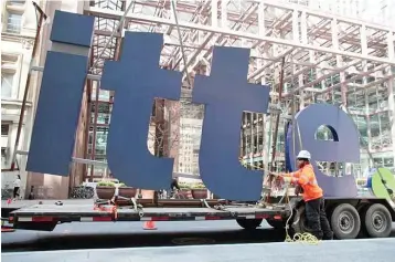  ??  ?? A worker guides part of a Deloitte sign before its installati­on on a new office building in downtown Toronto, Ontario. — Reuters photo