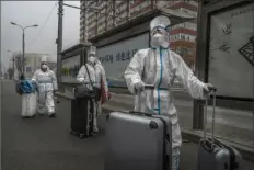  ?? Getty Images ?? Epidemic control workers wear protective suits as they carry their luggage in an area with communitie­s under lockdown to prevent the spread of COVID-19 on Thursday in Beijing.