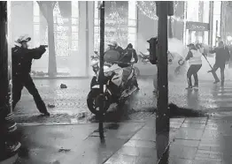  ?? LINE PRESS/GETTY-AFP ?? A French motorcycle officer points his gun at protesters after being assaulted during Saturday’s “yellow vest” protests. Officials defended the officer’s action.