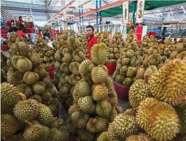  ?? — Reuters ?? ‘Gas’ leak: A durian vendor waits for customers at a market in Bangkok. Firefighte­rs were called to the RMIT university campus in Melbourne after a ‘gas’ smell was reported in a library.