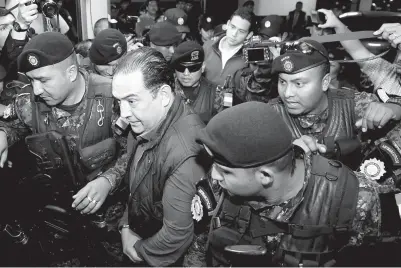  ?? — Gambar Reuters ?? SAMMY Morales (depan, tengah) dan Jimmy Morales (belakang, tengah) diiringi anggota keselamata­n ke mahkamah selepas ditangkap atas tuduhan rasuah di Kota Guatemala kelmarin.