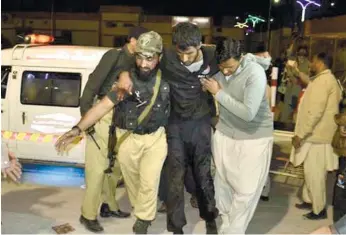  ?? (AP FOTO) ?? ONE OF THE SURVIVORS. A Pakistani volunteer and a police officer rush an injured person to a hospital in Quetta, Pakistan after two separate attacks in Pakistan. Gunmen stormed a police training center in the restive province of Baluchista­n Monday,...