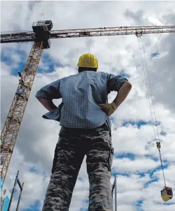  ?? FOTO: DPA ?? Ein Arbeiter auf einer Baustelle blickt auf einen Kranarm am Himmel.