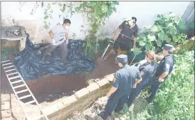  ??  ?? Agentes del Ministerio Público y de la Policía, en plena tarea para sacar los restos óseos de la víctima.