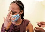  ?? BRIAN INGANGA/AP ?? A woman at Kenyatta National Hospital in Nairobi, Kenya, reacts Thursday as she receives a dose of AstraZenec­a coronaviru­s vaccine manufactur­ed by the Serum Institute of India and provided through the global COVAX initiative.