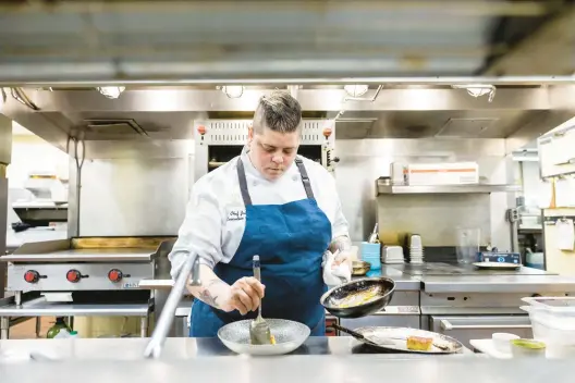  ?? KENDALL WARNER/STAFF ?? Executive Chef Julianne Gutierrez prepares a pan-roasted scallop dish at the Williamsbu­rg Inn on August 8.