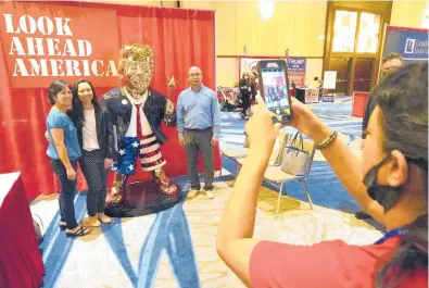  ?? JOHN RAOUX/AP ?? CPAC attendees pose for a photo next to a statue of former President Trump on Saturday in Orlando, Fla. There’s a possibilit­y Trump will run for president in 2024. But as the Trump Party takes over the GOP, anti-Trump Republican­s are abandoning the party in droves.