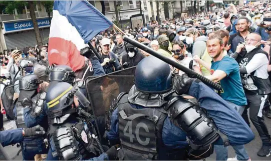  ??  ?? ENFRENTADO­S. Manifestan­tes chocan con funcionari­os policiales, ayer sábado, en París, durante la movilizaci­ón en rechazo del pasaporte sanitario y otras medidas.