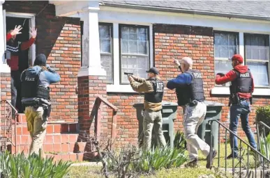  ?? STAFF PHOTOS BY ANGELA LEWIS FOSTER ?? Officers from various agencies point their weapons at a resident of Bennett Avenue in Chattanoog­a on Wednesday during a roundup to apprehend suspects who have outstandin­g warrants.