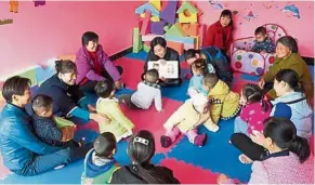  ?? —Xinhua ?? Relaxing time: Teachers and parents playing with the children during break at the centre in Wangjiapin­g village, Hubei province.