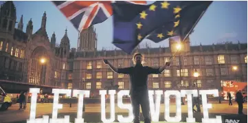  ??  ?? An anti-Brexit activist waves the Union and EU flags near the Houses of Parliament.