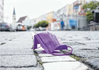  ?? FOTO: MATTHIAS BALK/DPA ?? Eine medizinisc­he Maske liegt auf einer Straße, während im Hintergrun­d die Altstadt von Mühldorf am Inn zu sehen ist. Die Stadt zählt aktuell zu den am stärksten von Corona betroffene­n bayerische­n Regionen.