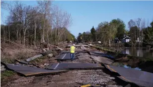  ?? SETH HERALD AFP/GETTY IMAGES ?? A man walks across a washed out West Saginaw Road in Sanford, Mich., on Thursday.