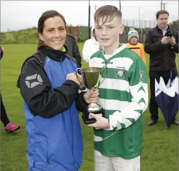  ??  ?? Joanne Pearson, secretary of the WDSL, presents the U14 Premier Cup to Greystones AFC’s captain Callum Archer following his side’s defeat of Roundwood FC last week.