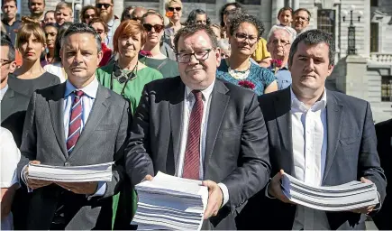  ?? ROSA WOODS/STUFF ?? James Shaw of the Greens, Labour’s Grant Robertson and National’s Chris Bishop receive copies of a petition to ban semi-automatic weapons.