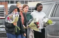  ?? ?? People bring flowers to a makeshift memorial outside Oxford High School in Michigan. Ethan Crumbley, 15, has been charged with murder and terrorism in the mass shooting.